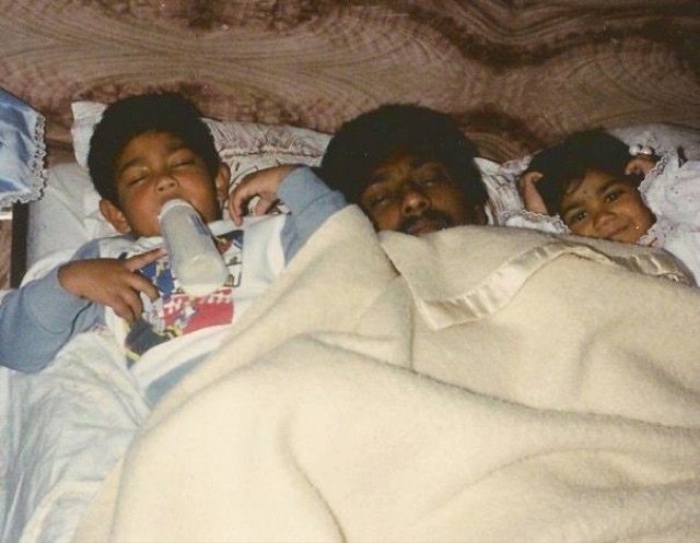 A film photo of Bob asleep with his two young children under a blanket