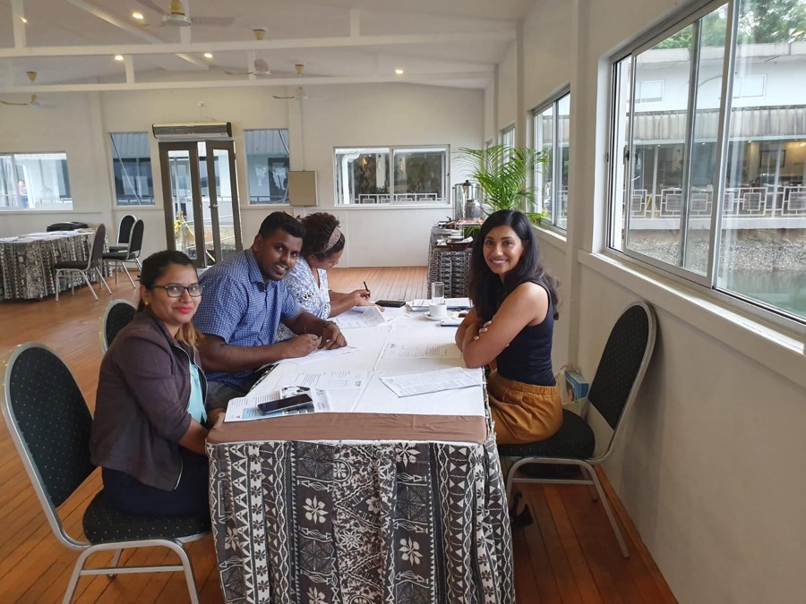 Shani at a table with three students in Fiji, going through application papers together